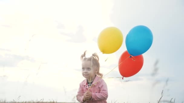 lánya kislány szórakozás fut lufikkal a születésnapján a szabadban mező. álmodj boldog családi koncepciót. életmód gyerek gyerek nap. gyermek fut, és léggömbök a háttérben a kék ég