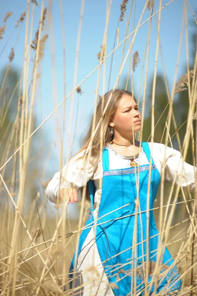 Girl in a blue sundress in a field of tall dry grass — Stock Photo, Image