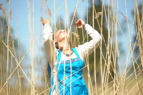 Dívka v modrém letní šaty v oblasti vysoké suché trávě — Stock fotografie