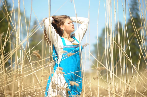 Meisje in een blauwe sundress op een gebied van hoge droog gras — Stockfoto