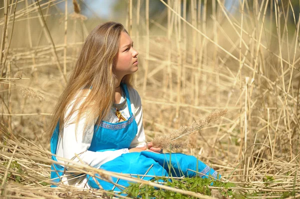 Girl in a blue sundress in a field of tall dry grass — Stock Photo, Image