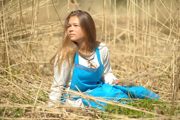 Meisje in een blauwe sundress op een gebied van hoge droog gras — Stockfoto