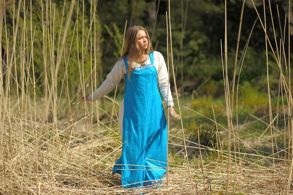 Девушка в синем сарафане в поле высокой сухой травы — стоковое фото