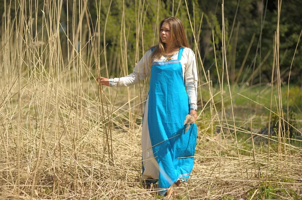 Fille dans une robe de soleil bleue dans un champ de haute herbe sèche — Photo