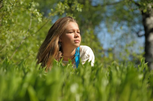 Jonge vrouw liggend op het groene gras — Stockfoto