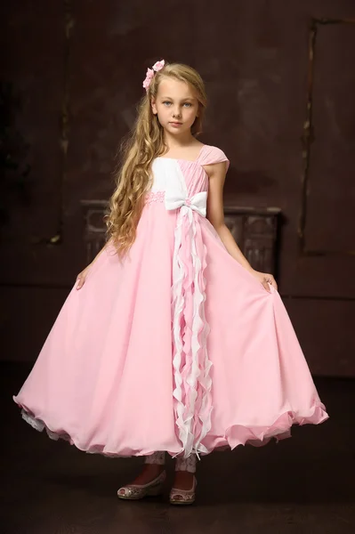 Beautiful young blonde girl with long hair in a pink princess dress. — Stock Photo, Image