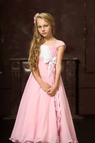 Mooie blonde meisje met lange haren in een roze prinses jurk. — Stockfoto