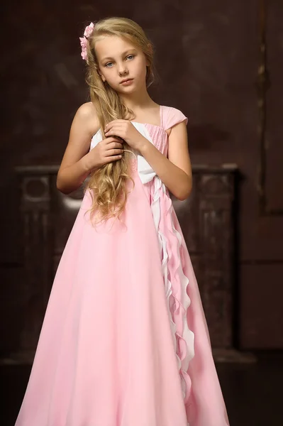 Beautiful young blonde girl with long hair in a pink princess dress. — Stock Photo, Image