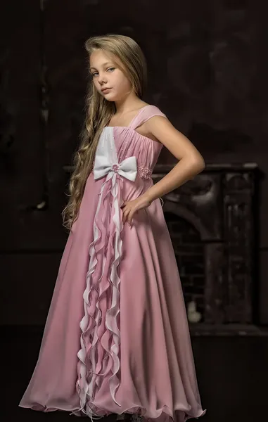 Beautiful young blonde girl with long hair in a pink princess dress. — Stock Photo, Image