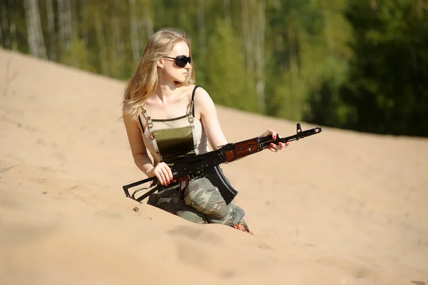 Ung blondin med ett gevär i händerna — Stockfoto