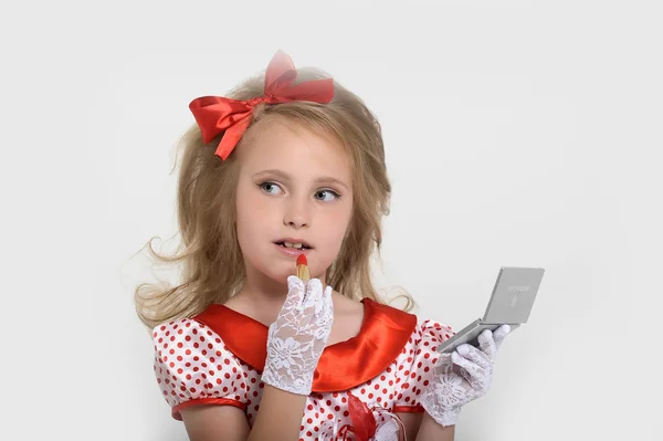 Little girl paints lips with lipstick