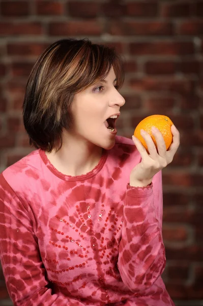 Mujer joven con naranja en la mano — Foto de Stock