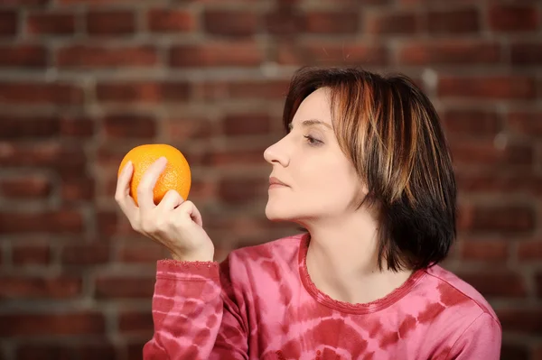 Mujer joven con naranja en la mano — Foto de Stock