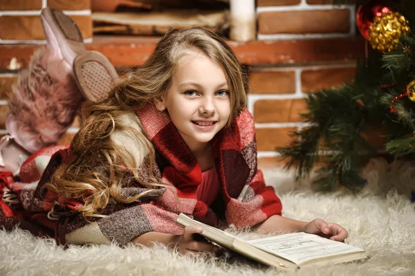 Chica leyendo un libro junto a la chimenea — Foto de Stock