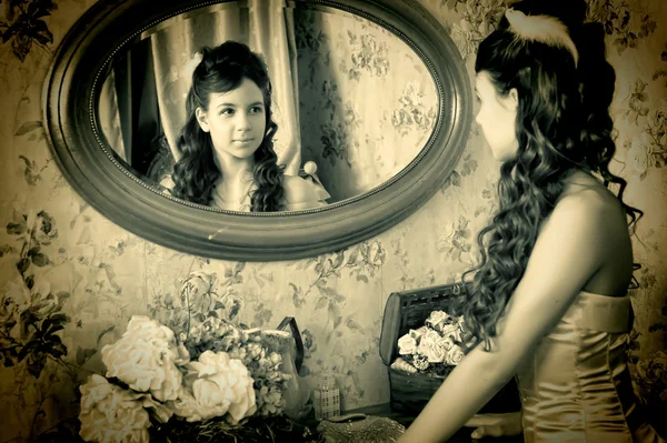 Beautiful young girl looking in the mirror — Stock Photo, Image