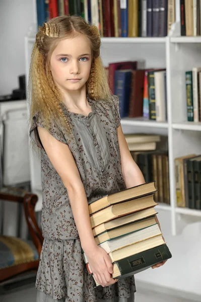 Дівчина з книгами в бібліотеці — стокове фото