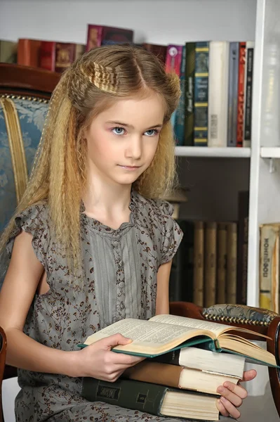 Mädchen in der Bibliothek mit einem Stapel Bücher — Stockfoto