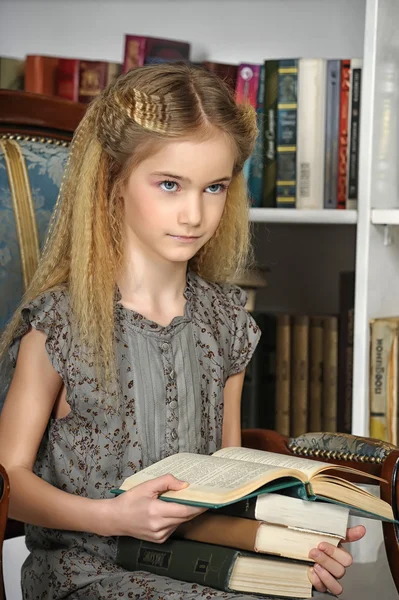 Menina na biblioteca com uma pilha de livros — Fotografia de Stock