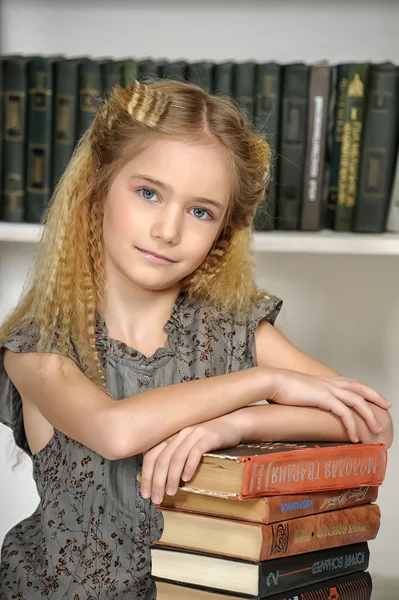 Mädchen in der Bibliothek mit einem Stapel Bücher — Stockfoto