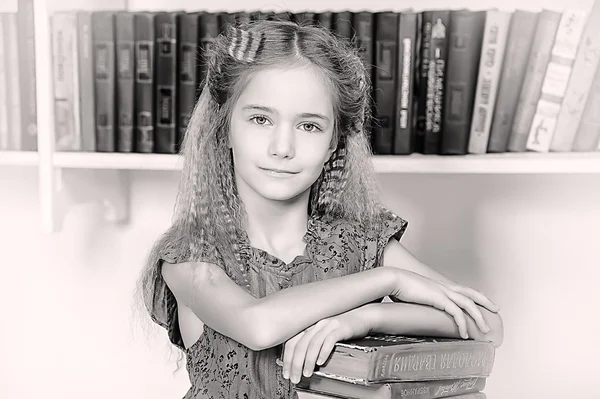 Menina na biblioteca com uma pilha de livros — Fotografia de Stock