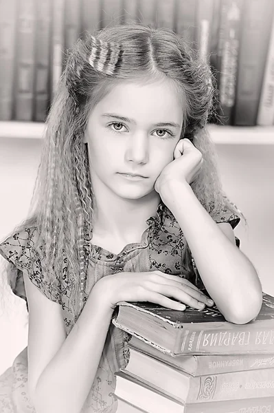 Mädchen in der Bibliothek mit einem Stapel Bücher — Stockfoto