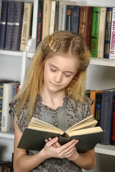 Κορίτσι με ένα βιβλίο σε μια βιβλιοθήκη — Φωτογραφία Αρχείου