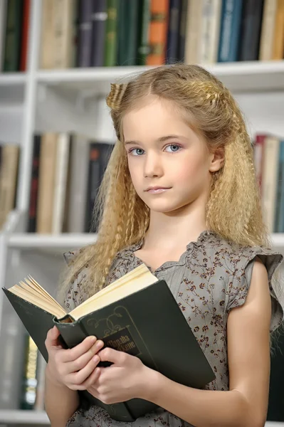 Mädchen mit einem Buch in einer Bibliothek — Stockfoto