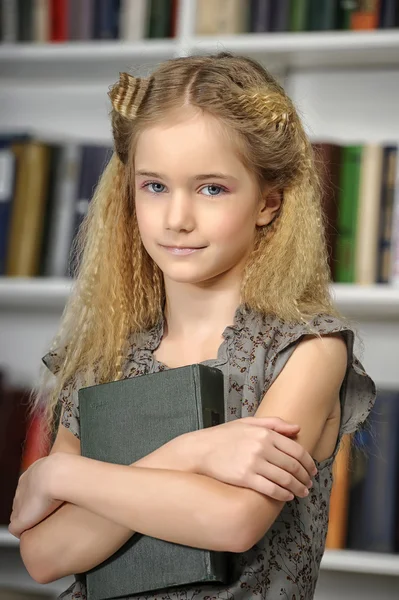 Mädchen in der Bibliothek mit einem Stapel Bücher — Stockfoto