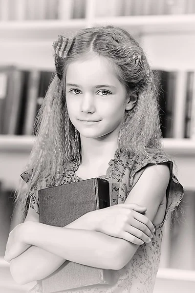 Mädchen in der Bibliothek mit einem Stapel Bücher — Stockfoto