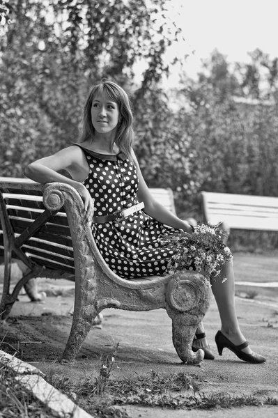 Kvinna med blommor på en bänk — Stockfoto