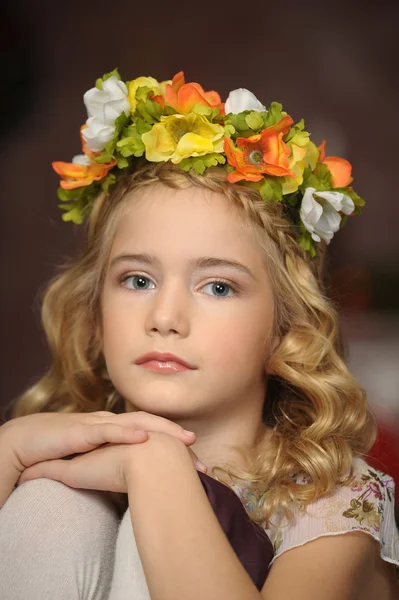 Retrato de uma menina com um ramo de flores na cabeça — Fotografia de Stock