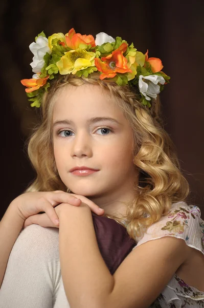Retrato de uma menina com um ramo de flores na cabeça — Fotografia de Stock