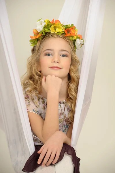 Retrato de uma menina com um ramo de flores na cabeça — Fotografia de Stock