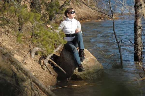 Tini lány ül egy szikla a víz — Stock Fotó
