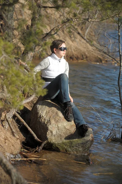 十几岁的女孩坐在一块岩石的水 — 图库照片