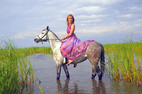 Mladá žena v šatech na koni ve vodě — Stock fotografie