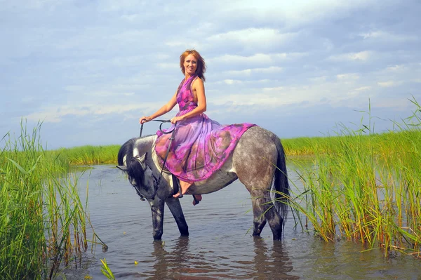 Mladá žena v šatech na koni ve vodě — Stock fotografie