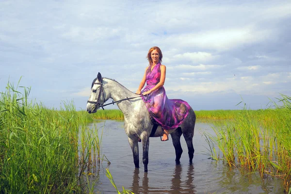 Jeune femme en robe sur un cheval dans l'eau — Photo