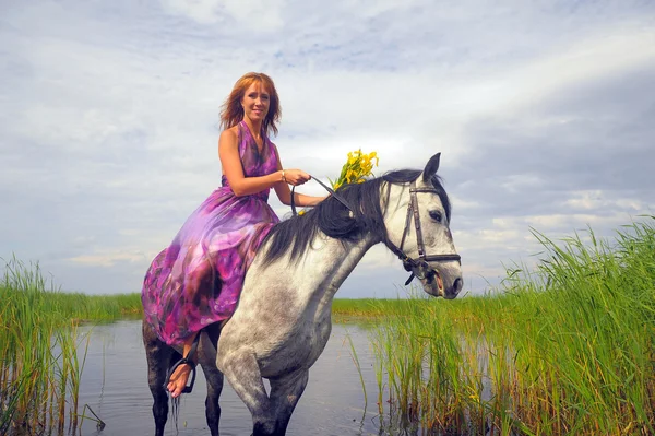 Jeune femme en robe sur un cheval dans l'eau — Photo
