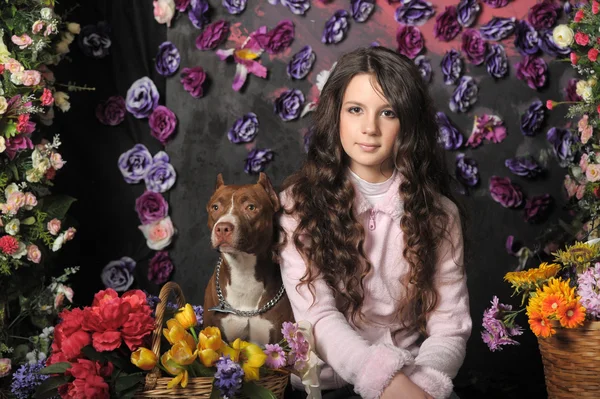 Vacker flicka med hund på en blommig bakgrund — Stockfoto