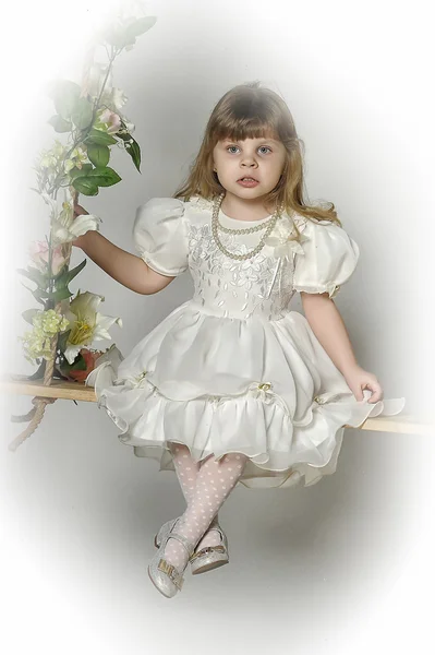 Petite fille sur une balançoire décorée de fleurs — Photo