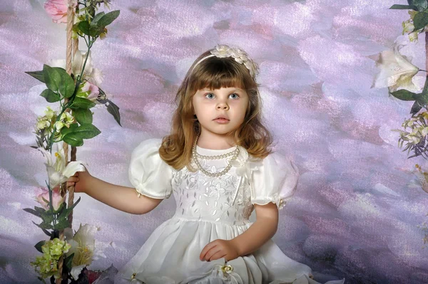 Niña en un columpio decorado con flores — Foto de Stock