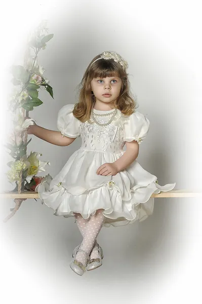 Маленькая девочка на качелях, украшенных цветами — стоковое фото