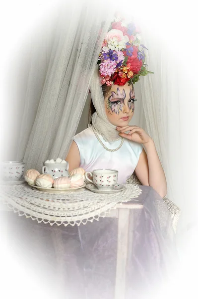 Beautiful girl with flowers on her head during a tea party — Stock Photo, Image