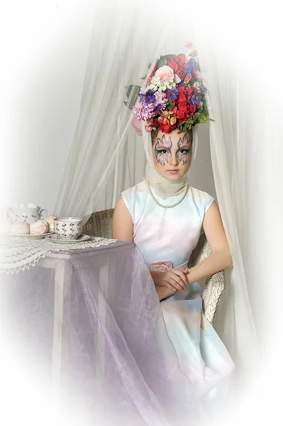 Menina bonita com flores na cabeça durante uma festa de chá — Fotografia de Stock