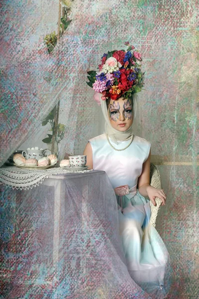 Beautiful girl with flowers on her head during a tea party — Stock Photo, Image