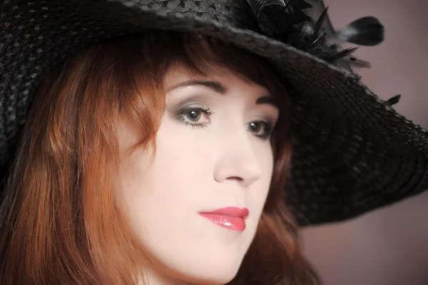 Retrato de una hermosa chica con un sombrero negro — Foto de Stock