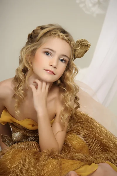 Portret van een mooi meisje in een gouden jurk — Stockfoto