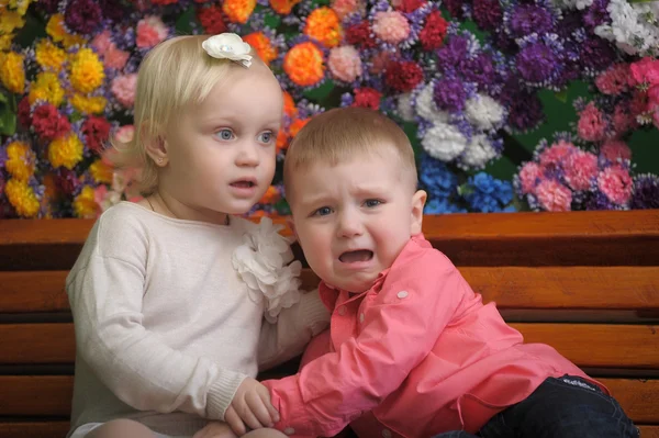 バック グラウンドで花とベンチ上の子供 — ストック写真