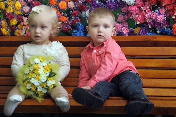 Crianças em um banco com flores no fundo — Fotografia de Stock